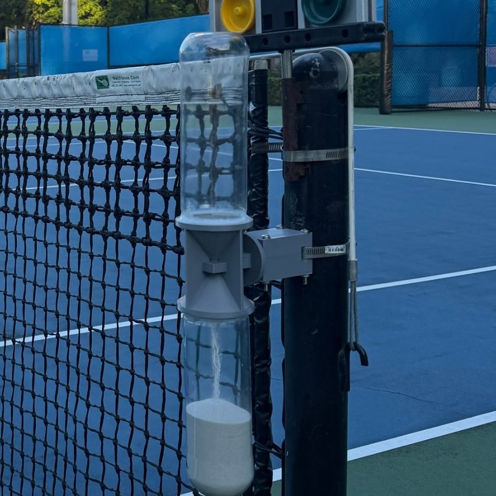 Close-up of the gray housing and its side arm, fixed to a black net post with a stainless-steel band clamp.