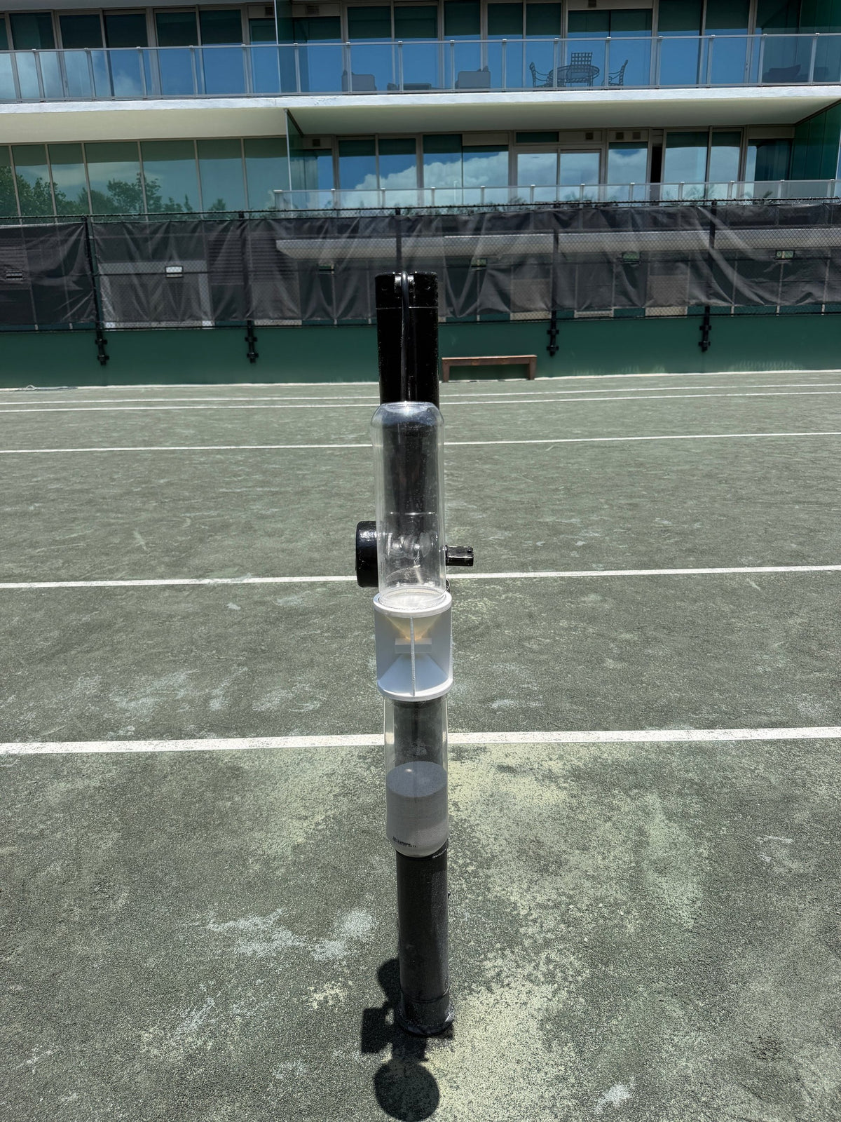 Ninety Post in white on a net post, seen head-on with the court behind.